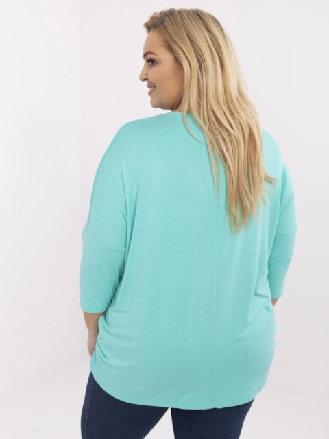 Modelka w turkusowej bluzce plus size RELEVANCE z napisem i dżetami