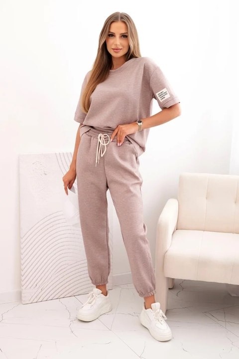 Modelka w komplecie damskim z wiskozy w odcieniu beżowego melanżu – luźna bluzka i spodnie z elastycznym pasem Modelka w komplecie damskim z wiskozy w odcieniu beżowego melanżu – luźna bluzka i spodnie z elastycznym pasem
