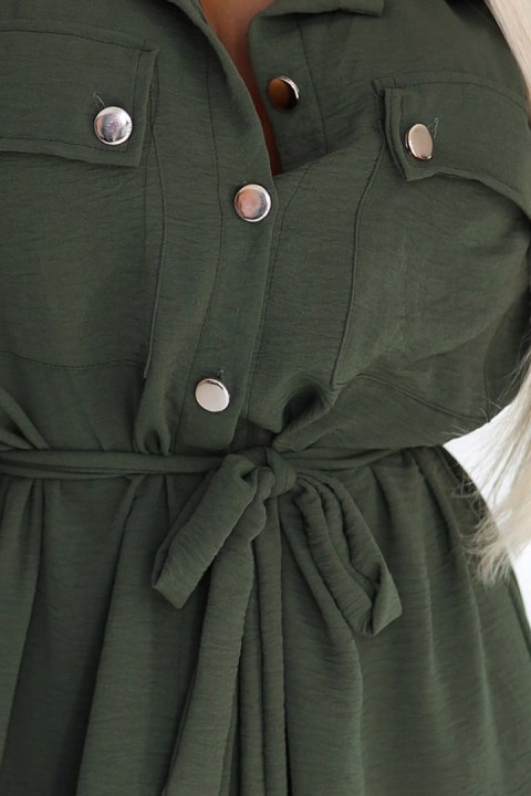 Kobieta w khaki szmizjerce midi z wiązaniem w talii i złotymi guzikami, modna stylizacja casual Kobieta w khaki szmizjerce midi z wiązaniem w talii i złotymi guzikami, modna stylizacja casual