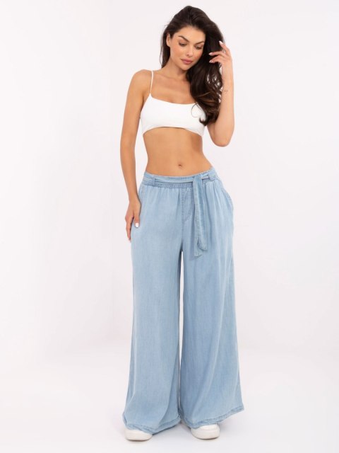 Modelka w jasnoniebieskich spodniach z cienkiego jeansu typu palazzo Modelka w jasnoniebieskich spodniach z cienkiego jeansu typu palazzo