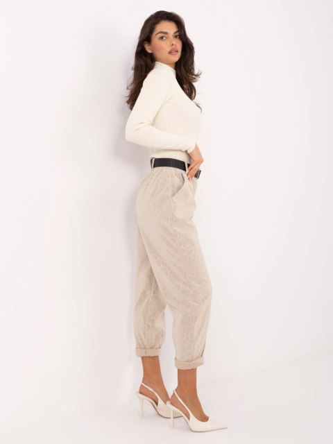 Modelka w jasnobeżowych spodniach z ekoskóry, jasny golf i szpilki – elegancki look