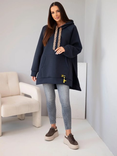 Modelka w granatowej bluzie oversize z kapturem i sznurkiem w panterkę oraz szarych jeansach