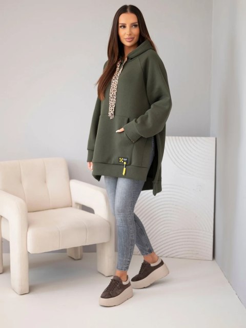 Modelka w bluzie oversize khaki z kapturem i sznurkiem w panterkę, widoczny dłuższy tył i boczne rozcięcie